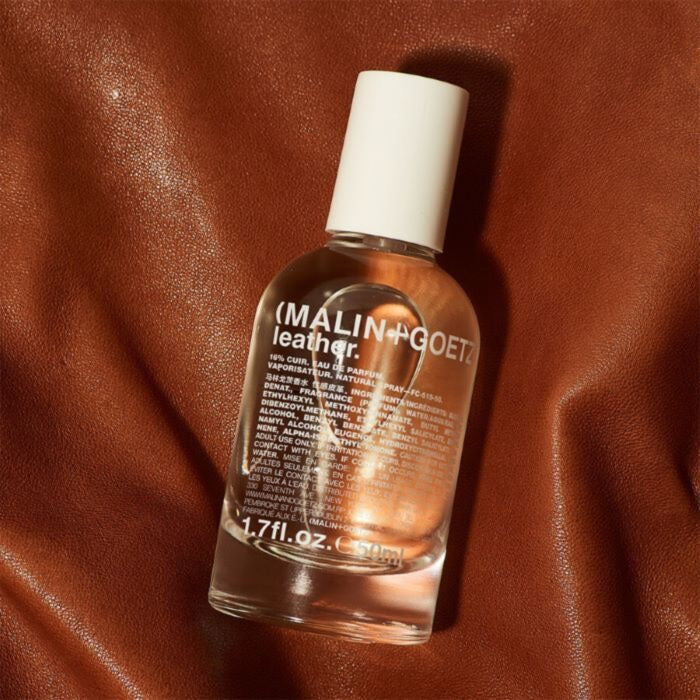 Malin+Goetz leather conditioner bottle on a brown leather background