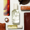 MALIN+GOETZ leather eau de parfum with other products including a bottle, roller ball, and comb on a white surface.