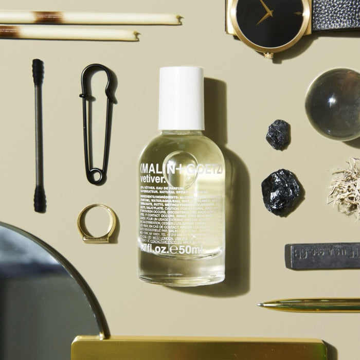MALIN+GOETZ bottle on a textured surface with various objects