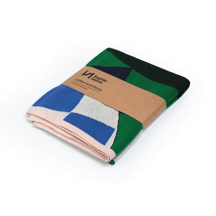 Folded multicolored throw blanket with a brand label on a white background