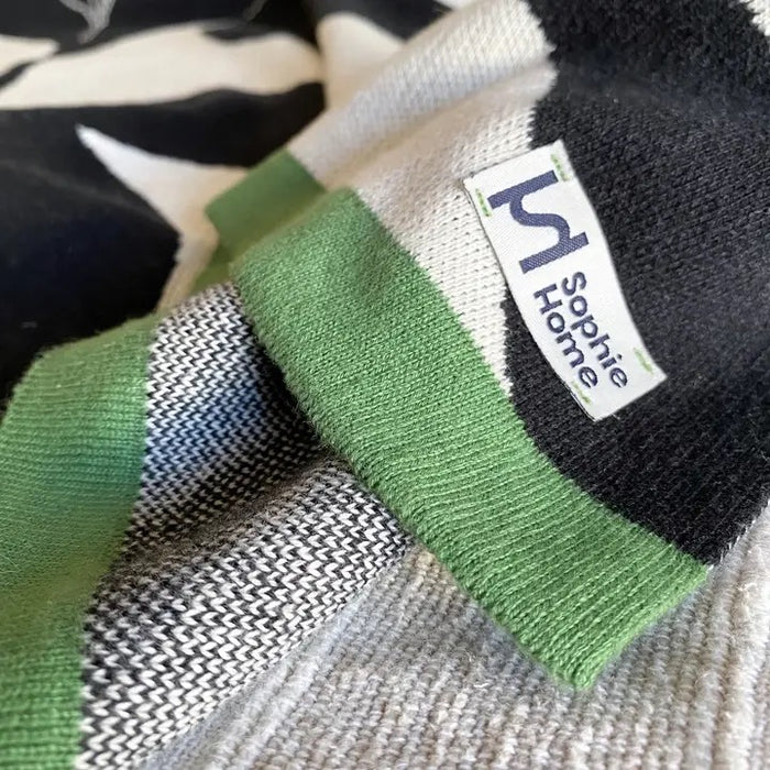 Close-up of a cotton throw with a Sophie Home label on a patterned background