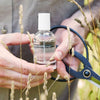 MALIN+GOETZ bottle held by hands with scissors and grasses in the background