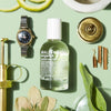 Bottle of Malin+Goetz bergamot eau de parfum on a green surface with decorative items.