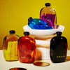 A display of brightly coloured glass bottles with lids filled with large coloured matches.