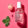 Malin+Goetz Strawberry perfume bottle with a strawberry and leaf on a pink background
