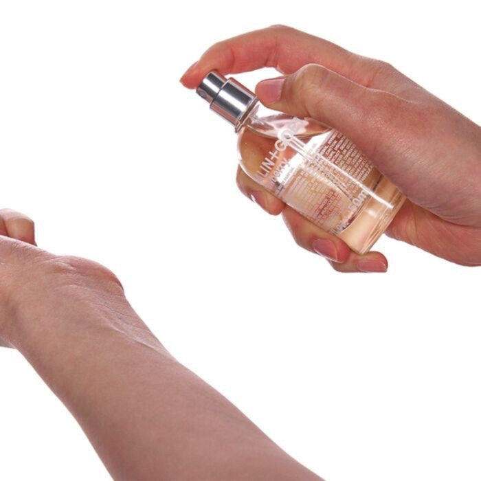 Hand holding a Malin+Goetz Strawberry perfume bottle with a white background