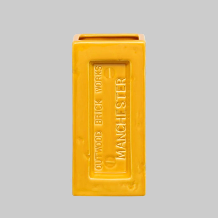 Yellow brick-shaped vase with 'Outwood Brick Works Manchester' text on a gray background