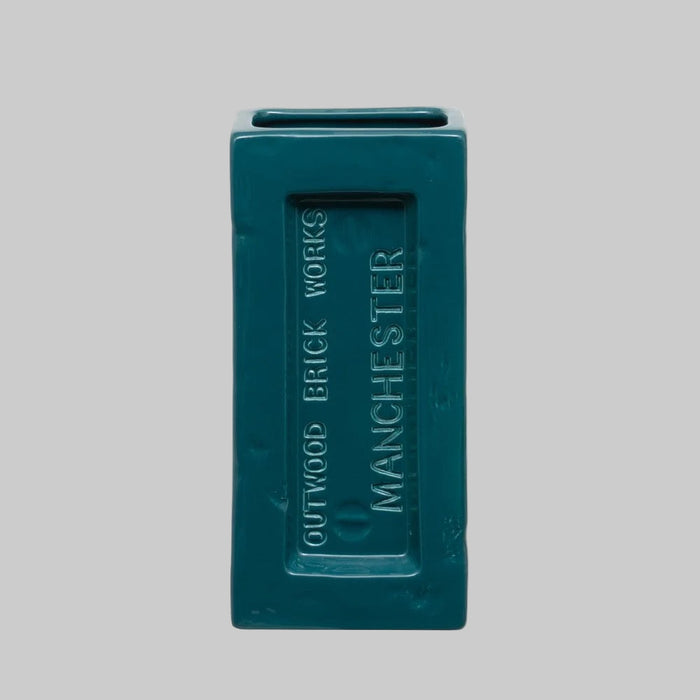 Teal brick vase with 'Outwood Brick Works Manchester' branding on a gray background. Perfect for design lovers who appreciate function with an industrial edge.