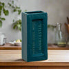 Teal ceramic vase with 'Manchester' text on a wooden surface.Perfect for design lovers who appreciate function with an industrial edge.