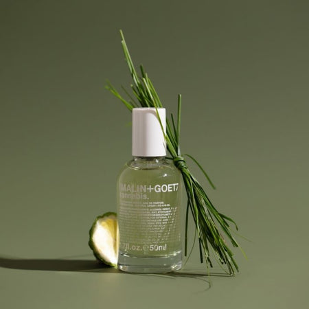 Cannabis perfume bottle with greenery on a green background