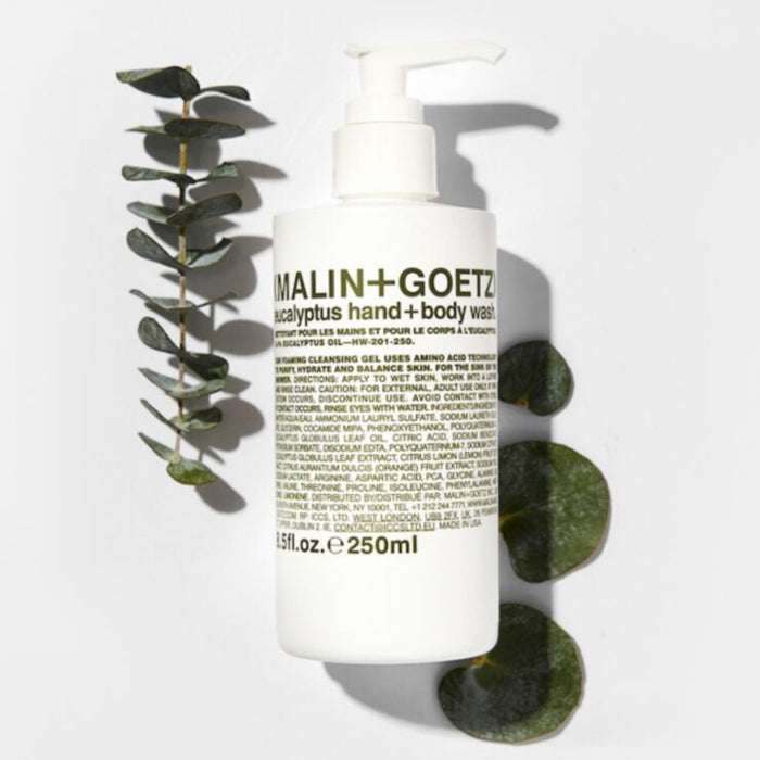 Malin+Goetz eucalyptus hand and body wash bottle with eucalyptus leaves on a white background