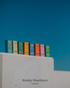 Colourful fragrances stacked on a concrete ledge with a clear blue sky in the background