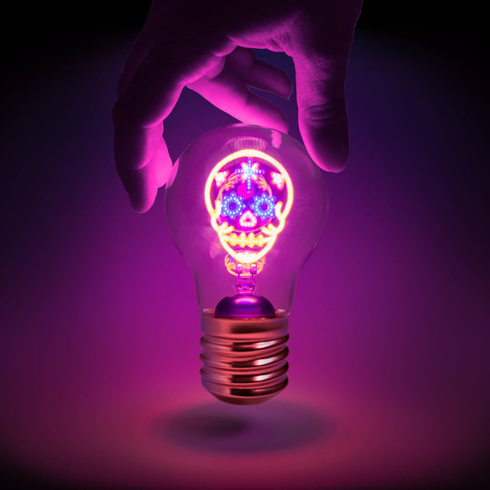 Rechargeable colourful skull light is glowing in various colours and held by a person's hand.