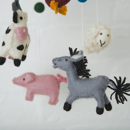 Felt animal toys and felt balls hanging from strings against a white background