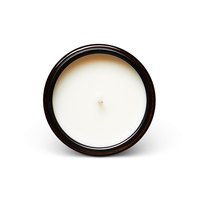 White candle in an amber glass jar on a white background