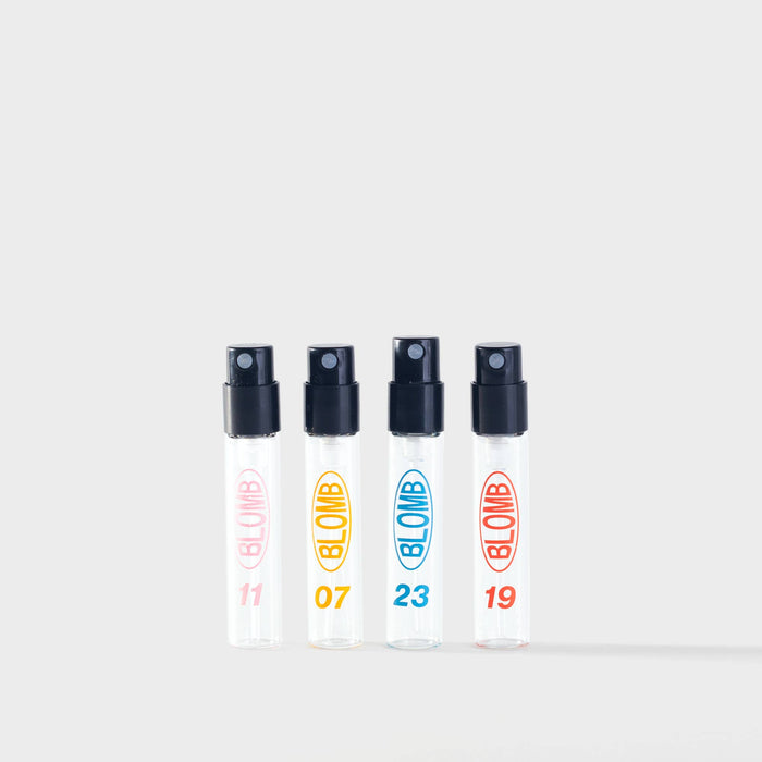 Four spray bottles of Blomb eau de parfum with black nozzles and colourful labels on a white background