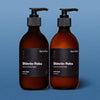 Two amber glass bottles with pump and black label on a blue background. Earl of East shinrin-yoku hand wash and hand balm.