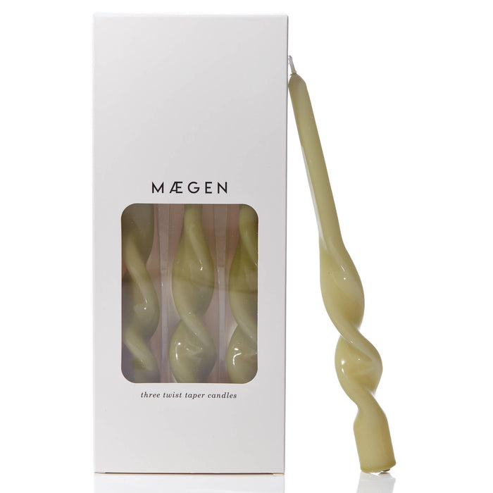 Twisted leaf green taper candle with 'Máegen' branded packaging and see through window on a white background