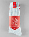 Pale blue sock with red packaging featuring a mountain design and Norwegian flag, on a gray background.
