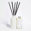 Elegant, white ceramic and reusable diffuser with black reeds and a glass bottle with aluminium screw top lid on a light background